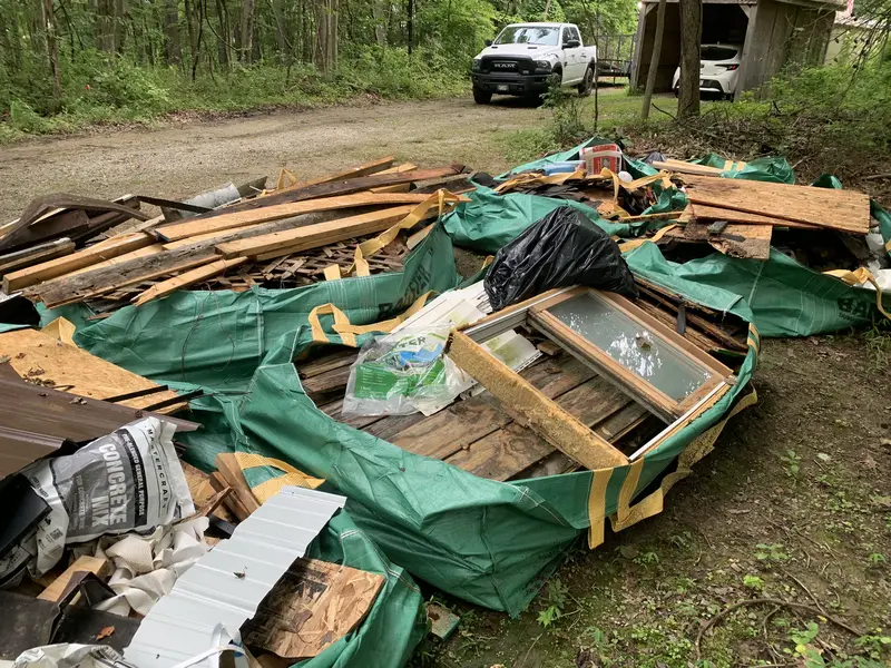 Pile of construction debris including wood planks, old windows, and tarps ready for removal after a home renovation or demolition project